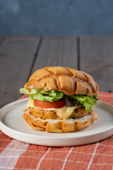 chicken burger with tomato lettuce onion and cheese in melon bun 