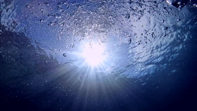 Under Water Film from tropical  Thailand - A stunning scene of striking sunlight breaking through ocean water with rising scuba diver air bubbles rising up to the surface