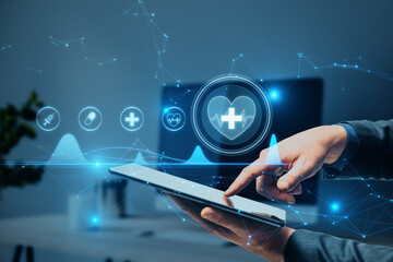businessman hand pointing at tablet with creative polygonal medical interface hologram on blurry hospital office interior background. Online healthcare, cardiology and technology concept. 