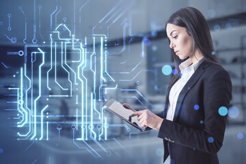 businesswoman using tablet with creative house chip circuit hologram on blurry office interior background and blue bokeh circles. Smart home, hardware and futuristic technology concept.