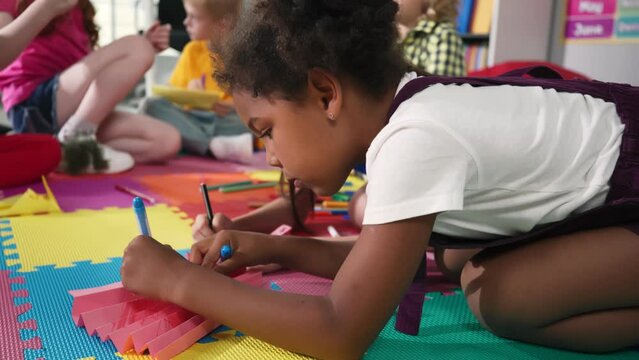 Closeup of African-American preschool girl draw on carpet in kindergarten