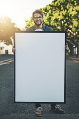 Happy young man holding copy space poster in the outdoors. Smiling guy with a big placard or sign for message design, advertising and marketing for events or branding in nature background.
