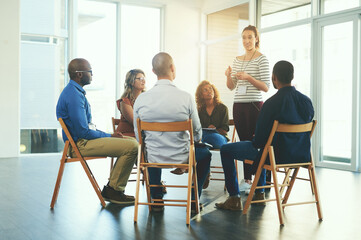 Female manager or CEO talking in a teamwork meeting about team development and success. Group of marketing team talking about a work strategy together in a coaching or training seminar at a company - obrazy, fototapety, plakaty