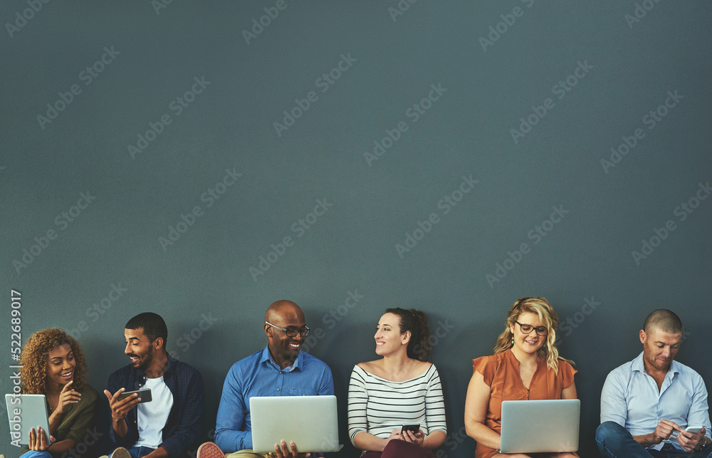 Poster group of happy business people sharing information on wireless technology in a row at an office toge