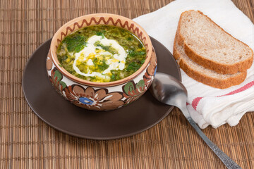 Portion of sorrel soup with chopped egg and sour cream