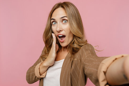 Close Up Young Surprised Employee Business Woman 30s She Wearing Casual Classic Jacket Doing Selfie Shot Pov On Mobile Cell Phone Cover Mouth With Hand Isolated On Plain Pastel Light Pink Background.