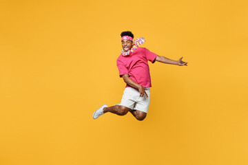 Young happy fun exultant jubilant expressive man 20s he wear pink t-shirt near hotel pool jump high...