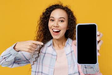 Young black teen girl student wear casual clothes backpack bag use close up mobile cell phone blank screen workspace area isolated on plain yellow background. High school university college concept.