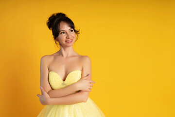Smiling beautiful middle-aged woman on a yellow background in the studio.
