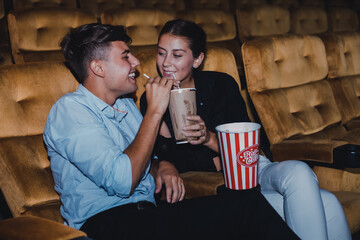 Caucasian white couples enjoying a movie having a drink in the cinema.
