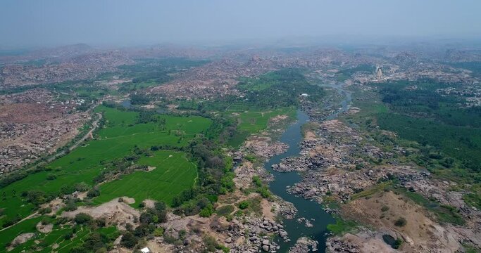 Aerial shot of rocky bouldery landscape and rice fields along river