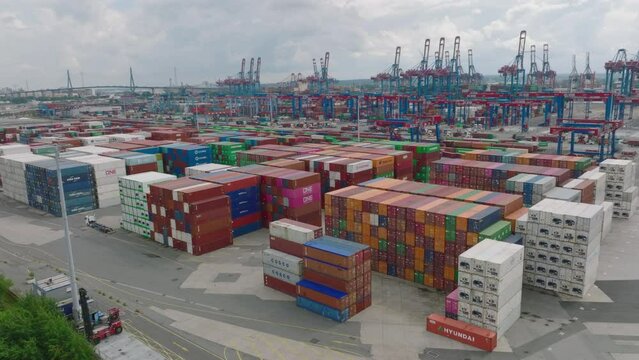 Aerial ascending footage of varied colour standardised containers stacked in large harbour. Important transport crossroads for importing and exporting abroad. Hamburg, Germany