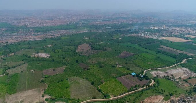 Aerial shot of countryside with fields, boulders hills and temple behind