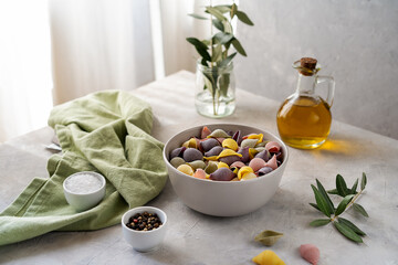 Colorful Italian pasta conchiglie or seashells in bowl, olive oil, salt, pepper, olive branch over concrete background 