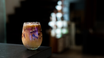 Ice coffee on a table with cream being poured into it showing the texture