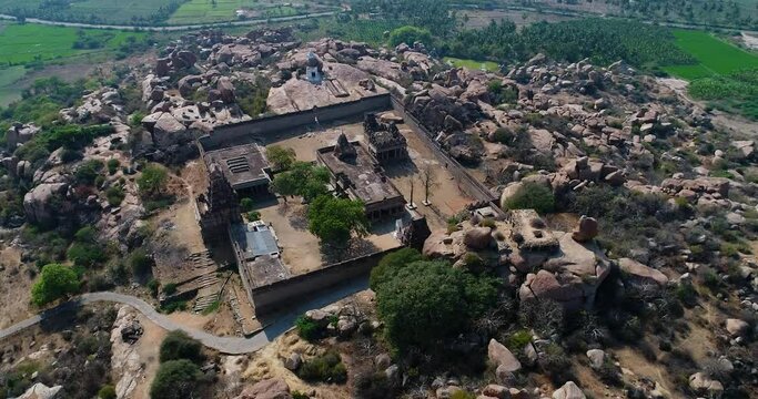 Aerial shot of rocky landscape with bouldery hills, hindu temple on top