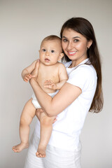 A portrait of a beautiful young mother and her sweet baby in a diaper. Motherhood. Happy family
