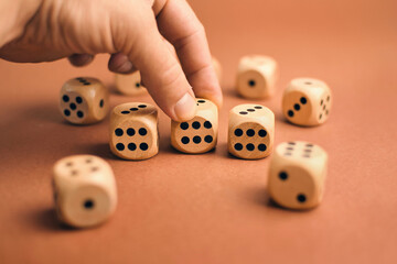 Hand holding wooden dices with numbers on brown background 