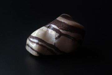 Zebra jasper chalcedony tumbled stone macro isolated on black background