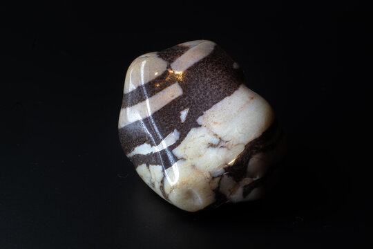 Zebra jasper chalcedony tumbled stone macro isolated on black background