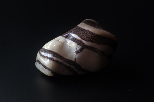 Zebra jasper chalcedony tumbled stone macro isolated on black background