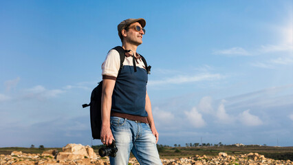 Naklejka premium Professional travel blogger and photographer with backpack and photographic equipment. Low angle view of travel photographer with camera in hand to create content for social networks and agencies