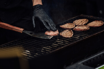 Chef making burger meat at the open air restaurant grill. Festival food, fast food restaurant