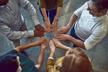 Business people making circle with hands, doing team building and showing support standing together at work from above. Colleagues making shape with fingers and expressing unity, trust and community