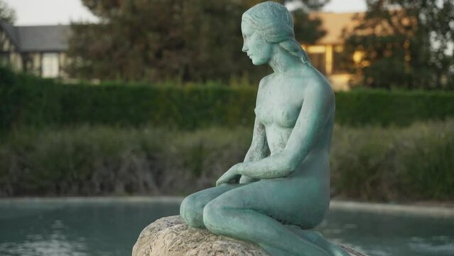 Statue of a naked woman sitting on a rock in a water fountain 