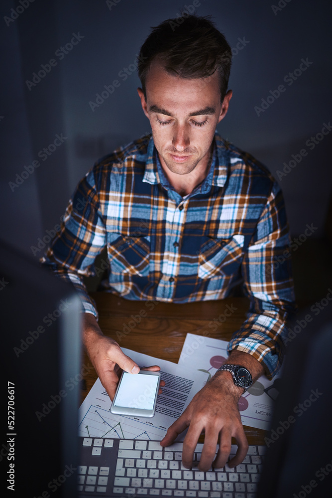 Leinwandbilder businessman reading a message on his phone and working on his computer in the office. corporate prof