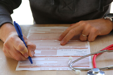 Docteur remplissant feuille de remboursement s&eacute;curit&eacute; sociale pour une consultation