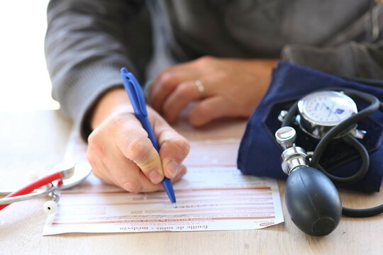 Docteur remplissant feuille de remboursement s&eacute;curit&eacute; sociale pour une consultation