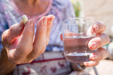 elderly person takes his medication with a glass of water