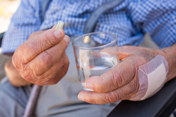 elderly person takes his medication with a glass of water