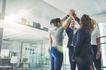 Team number one. Successful group of business people giving a high five in support team building...