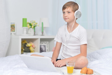 Boy listening to music on bed  while having breakfast