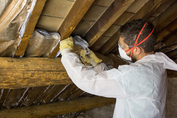 Worker with glasses and protective mask isolating the ceiling