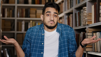 Close-up young upset man standing indoors in university library hispanic student misunderstood...