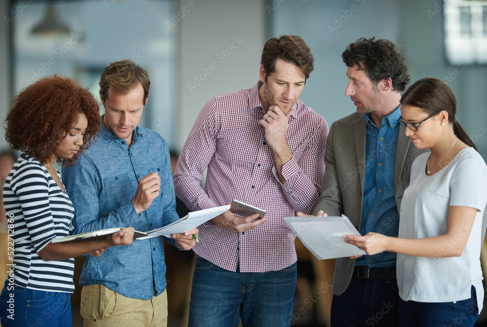 Poster Colleagues talking about paperwork while standing in the office together. Business people working together to discuss strategy while using wireless devices. Tech savvy ways to save time in your job.