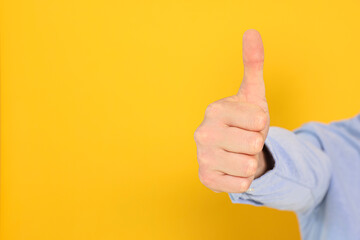 Man showing thumb up on orange background, closeup. Space for text