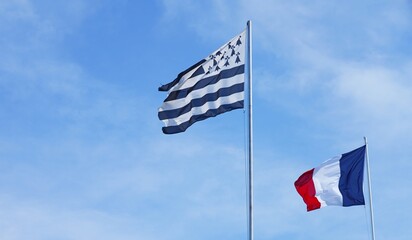 View of the French flag and Breton flag flying side by side in Brittany, France