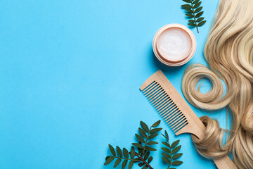 Flat lay composition with lock of healthy blond hair on light blue background. Space for text