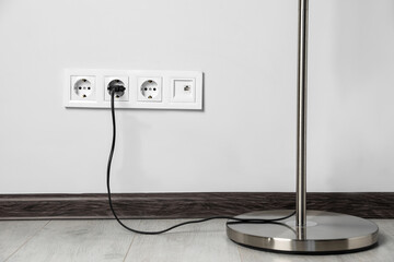 Floor lamp plugged into wall power socket indoors