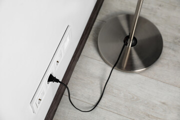 Floor lamp plugged into wall power socket indoors, above view