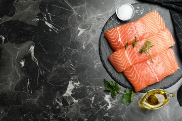 Flat lay composition with fresh raw salmon on black marble table, space for text. Fish delicacy