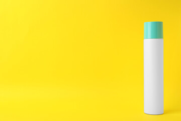 Bottle of dry shampoo on yellow background. Space for text