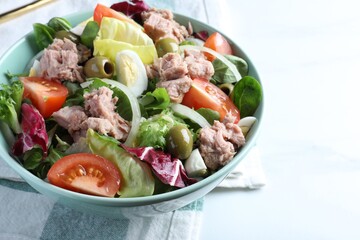 Bowl of delicious salad with canned tuna and vegetables on white table, closeup. Space for text