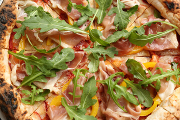 Tasty pizza with meat and arugula as background, top view