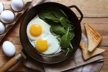 Delicious fried egg with spinach served on wooden table, flat lay
