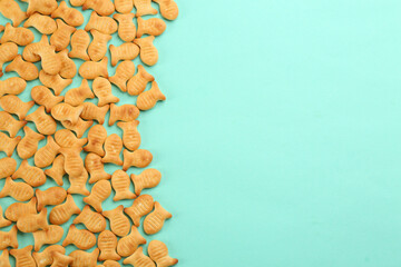 Fototapeta na wymiar Delicious goldfish crackers on turquoise background, flat lay. Space for text